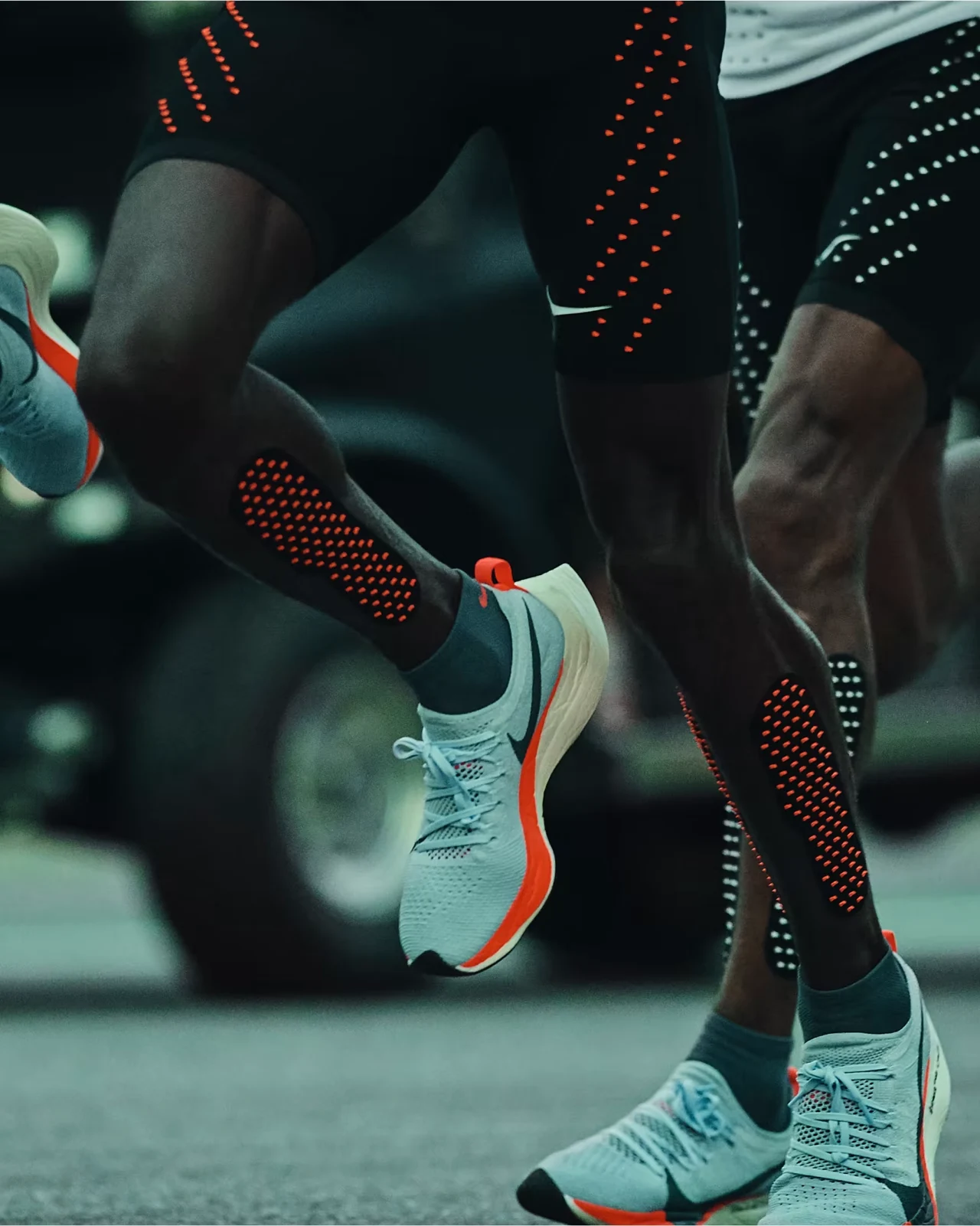 Runners in Breaking2 kit, with pale blue Vaporfly Elite shoes suspended mid-stride.