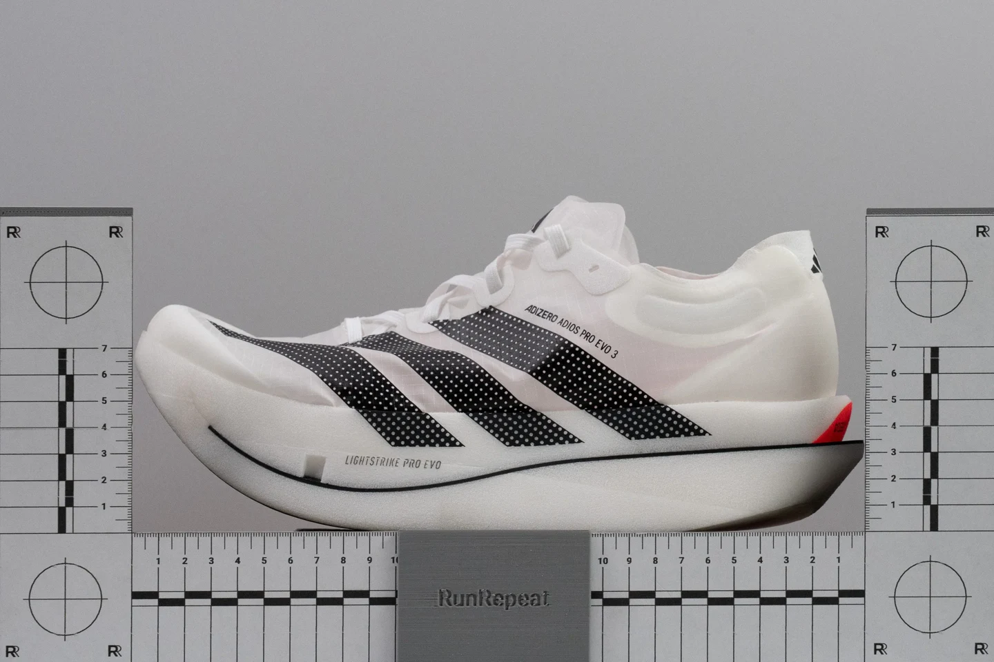 The same Adidas model in profile between measuring rulers, showing its curved forefoot and heel.