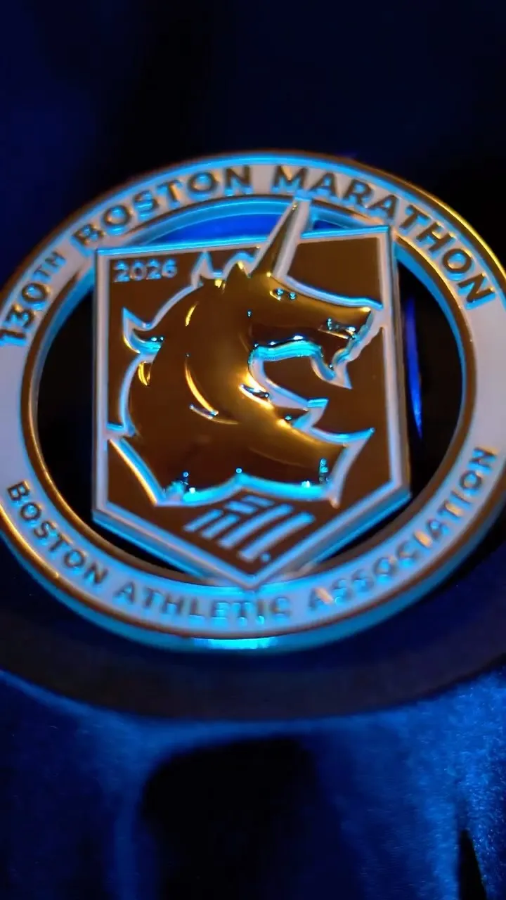 The gold Boston Marathon 2026 medal: the B.A.A. unicorn inside a ring reading “130th Boston Marathon” and “Boston Athletic Association”.