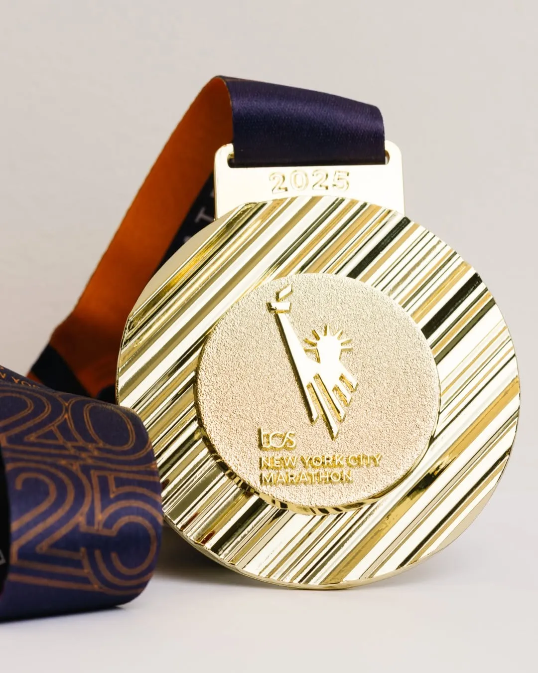 The gold 2025 New York City Marathon medal with its ribbed rim.