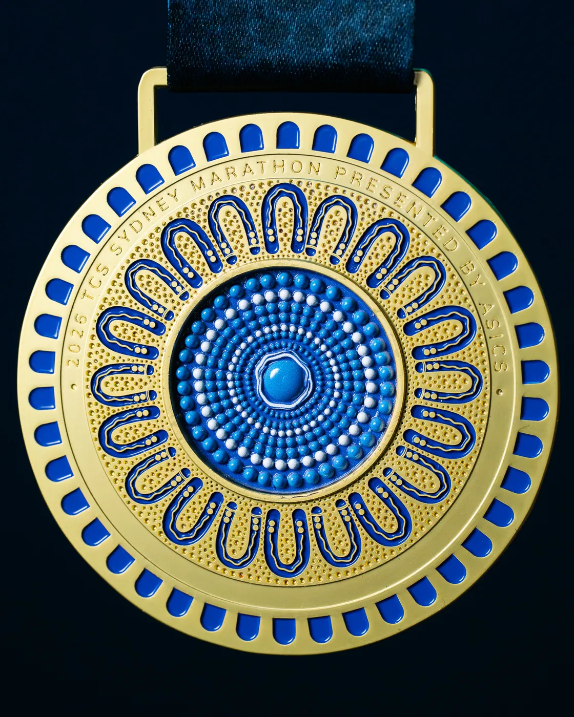 The front of the Sydney Marathon 2026 medal: gold with concentric blue dot-work rings.