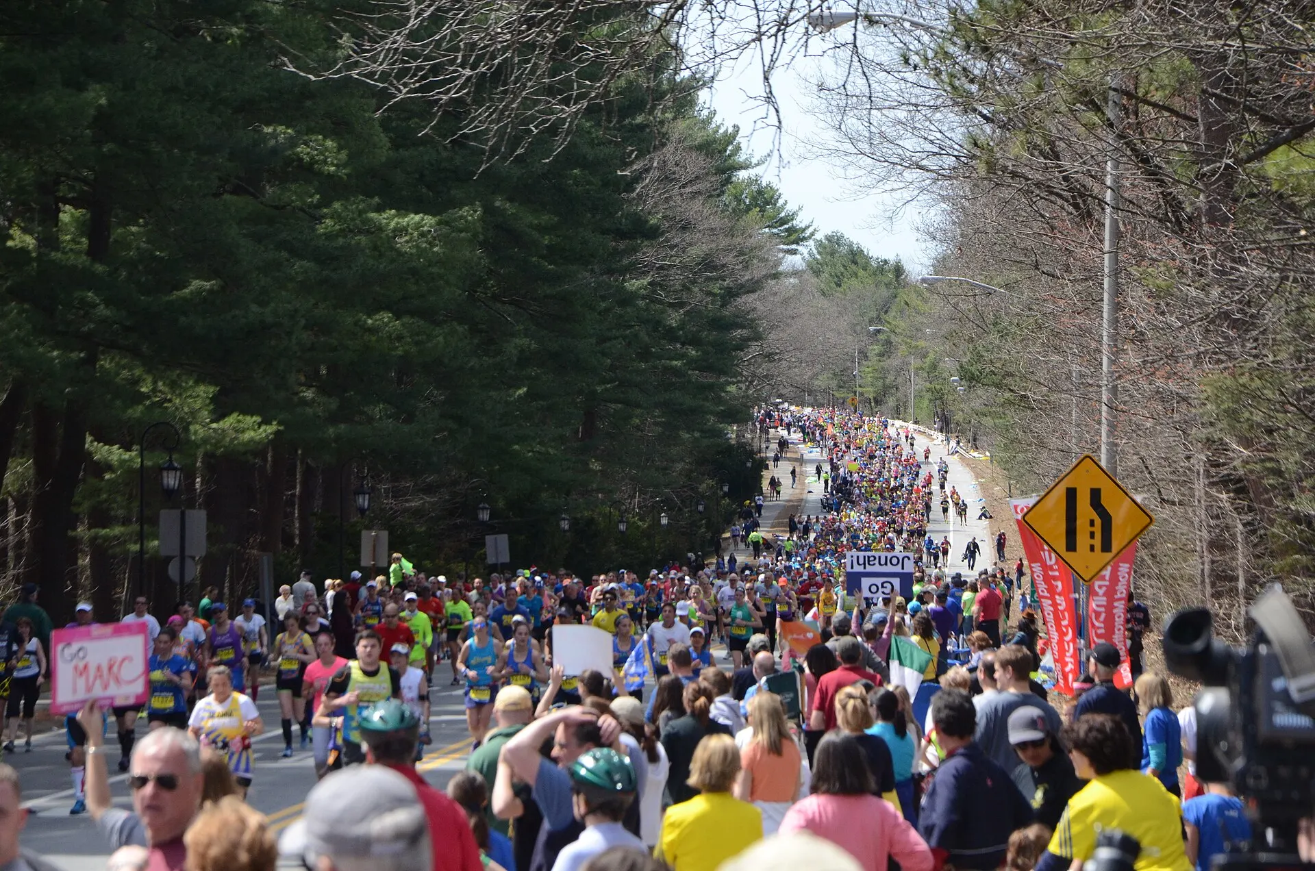 A dense field of runners on a tree-lined road past Wellesley College during the 2014 Boston Marathon.